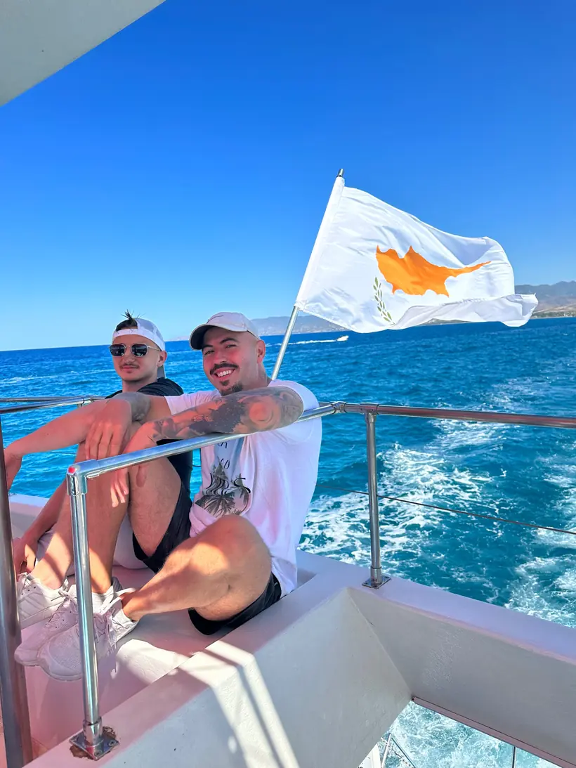 Adrian mit einem Freund auf einem Boot vor der Küste Zyperns, zyprische Flagge im Wind