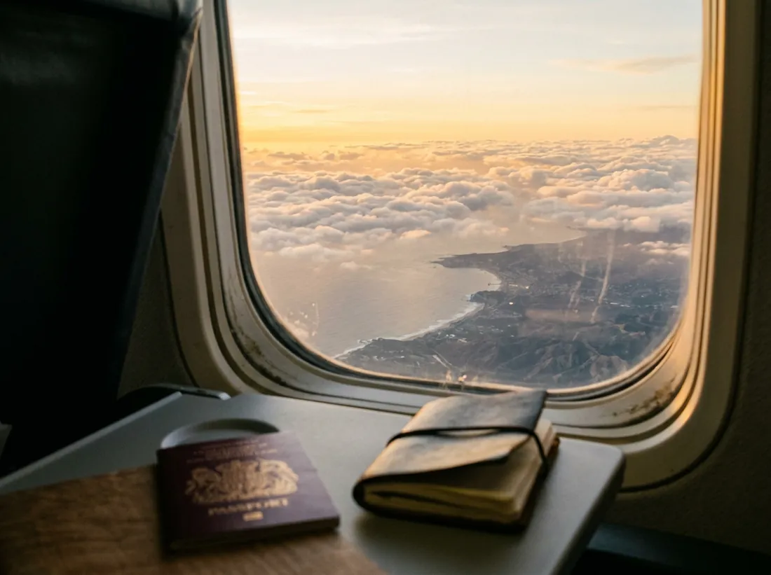 Blick aus dem Flugzeugfenster über Wolken im Abendlicht