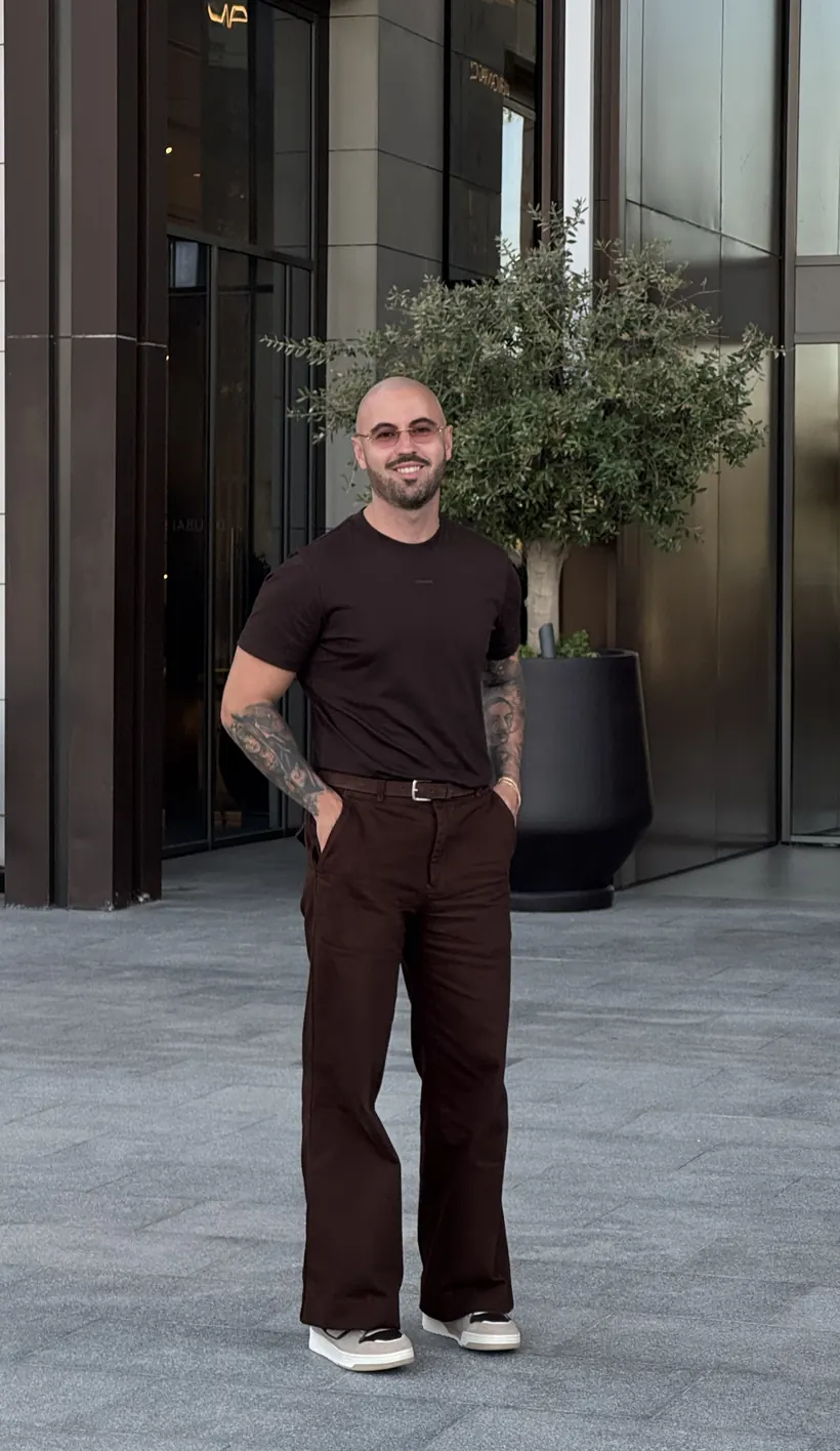 Adrian in brauner Kombination vor einer modernen Fassade